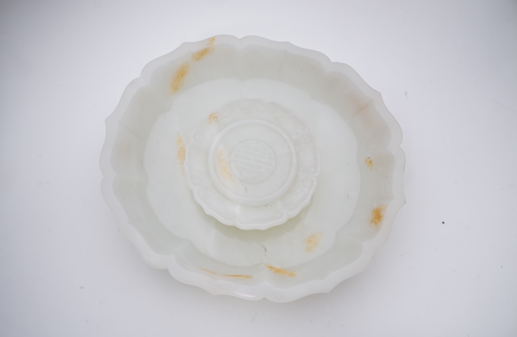 A Chinese white and russet jade petal lobed cup stand